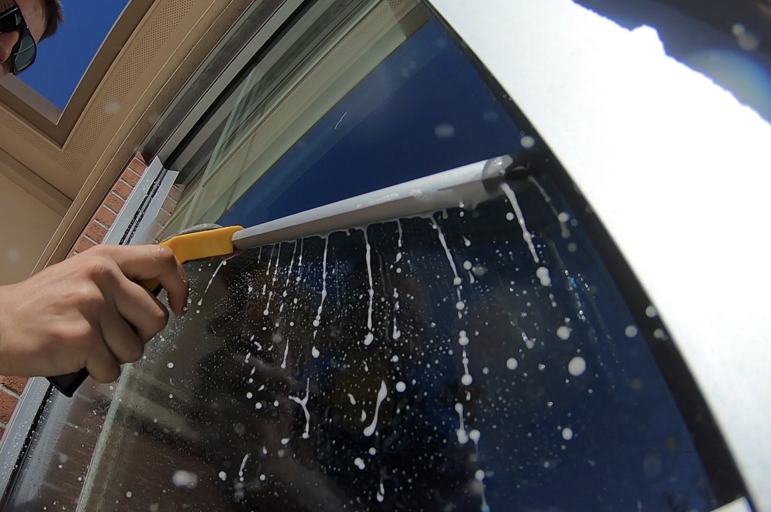 A squeegee cleaning a soapy exterior window